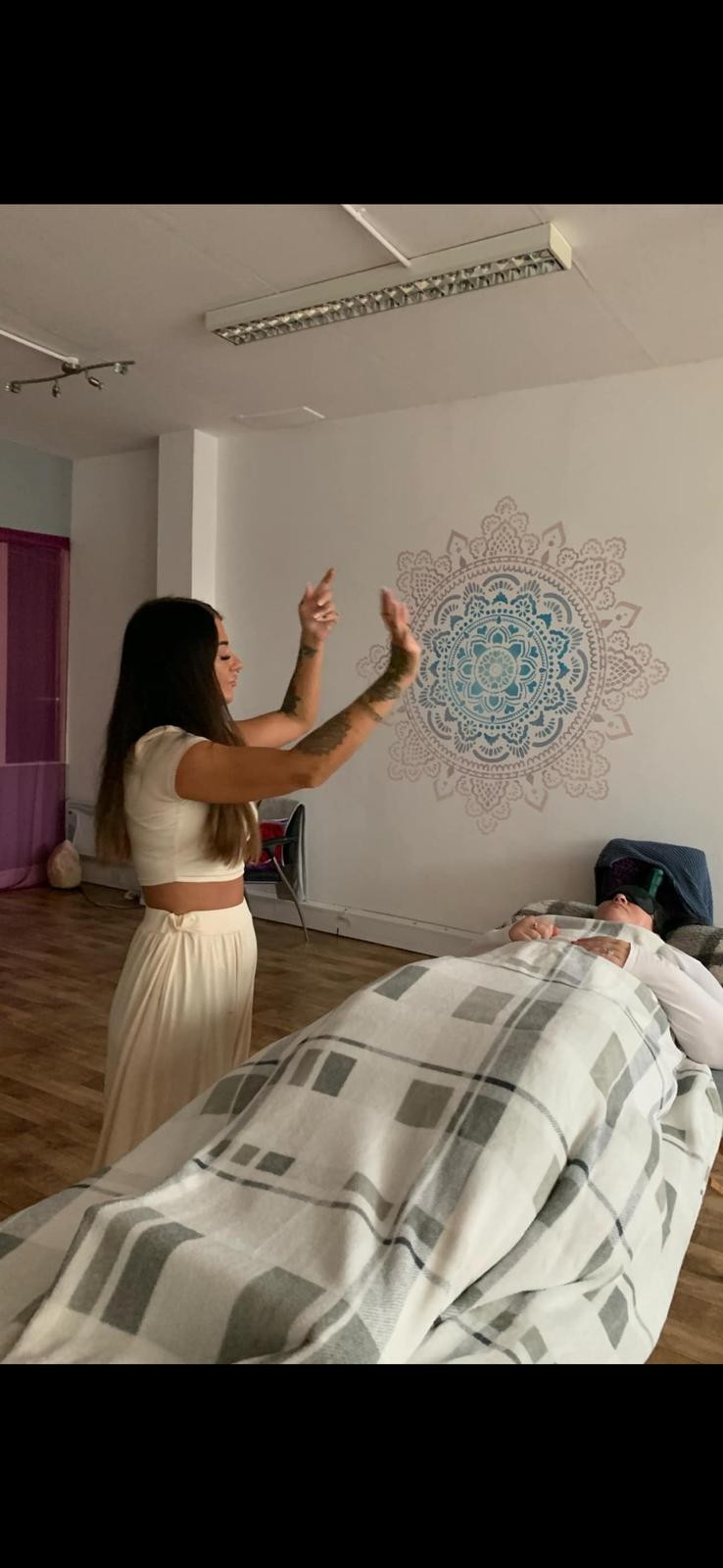 Kate performing energy work in her healing studio with mandala backdrop